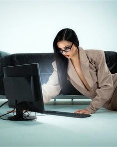 a woman leaning on the floor in front of a computer