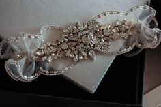 a bridal garter in a black box with white fabric and silver beading