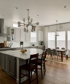 a large kitchen with an island in the middle and chairs at the counter top on the side