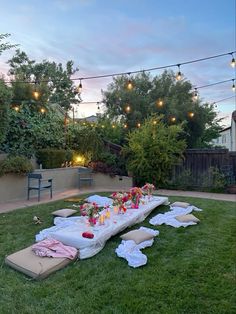 a long table set up in the middle of a yard with candles and flowers on it