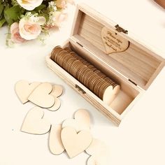 four wooden hearts in a box next to some flowers and a vase with pink roses