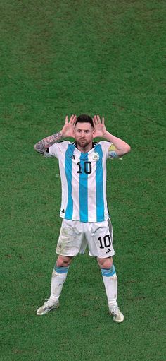 a man standing on top of a soccer field holding his hands up