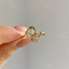 a woman's hand holding a gold ring with two diamonds