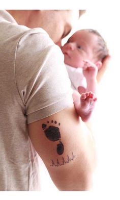 a man holding a baby in his arms with a hand and foot print on it