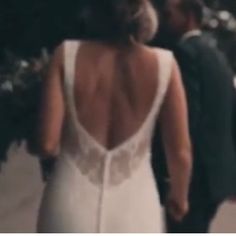 the back of a woman's wedding dress as she walks down the street with her husband