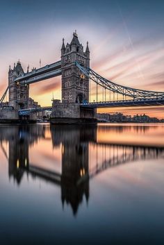 the tower bridge is reflecting in the water