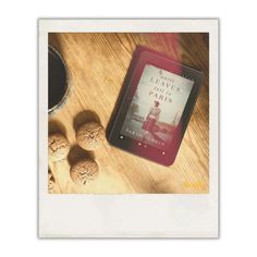 a book sitting on top of a wooden table next to some nuts and a cup