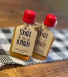 two small bottles of honey sitting on top of a wooden table next to each other