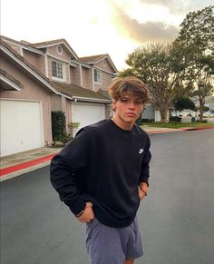 a young man standing in the middle of a street with his hands on his hips