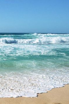 an ocean view with waves crashing on the beach