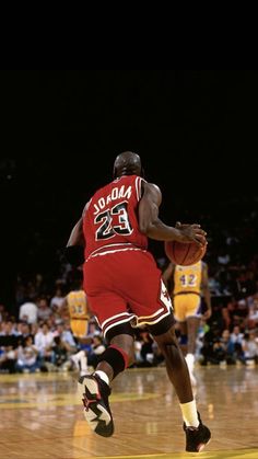 a basketball player dribbling the ball in front of an audience at a game