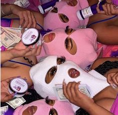 several women in pink masks are laying on the ground with money around them and one woman has her eyes closed