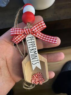 a hand holding a wooden spoon with peppermint candies in it and a tag that says peppermint candy