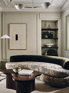 a living room filled with furniture and a painting on the wall next to a coffee table