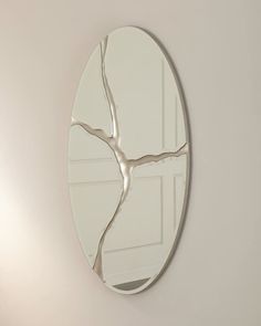 a round mirror hanging on the wall next to a white door with a tree branch in it