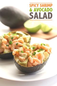 an avocado filled with shrimp and garnished with scallions on a white plate