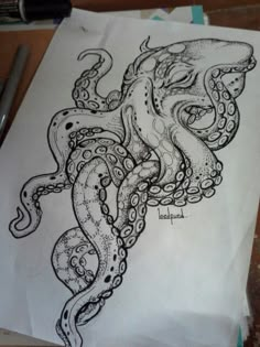 an octopus drawing on white paper next to a pen and ink marker with black ink