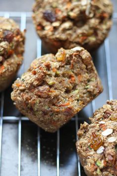 several muffins on a cooling rack with nuts and other food items in the background