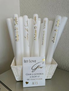 white candles with gold lettering in a basket on top of a table next to a sign that says let love grow