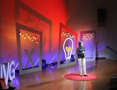 a woman standing on top of a red rug in front of a wall with lights