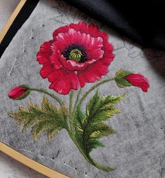 a close up of a piece of cloth with embroidery on it and a red flower