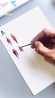 someone is holding a pencil and drawing people on a piece of paper with colored crayons