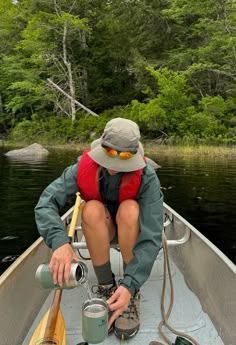 a man sitting in the back of a boat holding a fishing pole and two buckets