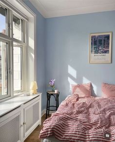 a bed sitting in a bedroom next to a window filled with lots of light blue walls