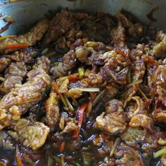 meat and vegetables are being cooked in a pan