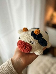 a hand holding a small crocheted cow