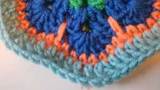 there is a crocheted blue and orange square on top of a white surface