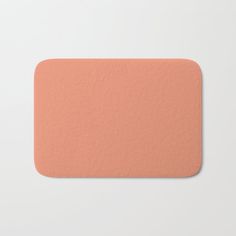 an orange colored bath mat on a white surface with the top corner slightly tilted down