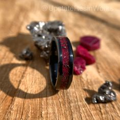 a couple of rings sitting on top of a wooden table next to rocks and stones