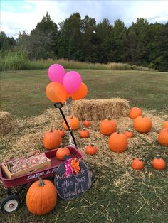 there is a wagon full of pumpkins with balloons in the air and hay bales behind it