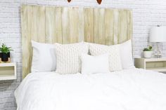 a bed with white sheets and pillows in a bedroom next to two wooden headboards