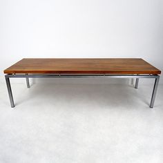 a wooden table sitting on top of a white floor next to a metal frame wall