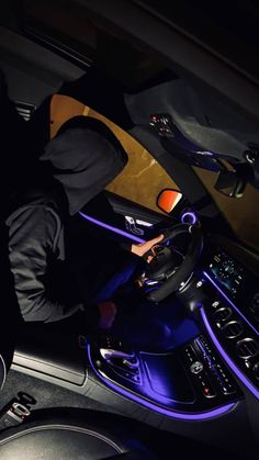 a man sitting in the driver's seat of a car with his hands on the steering wheel