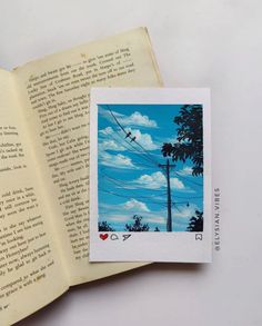 an open book sitting on top of a table next to a phone pole and telephone wires