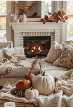 a living room filled with lots of white furniture and pumpkins on the coffee table