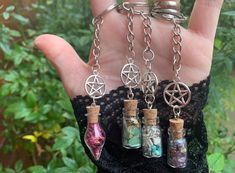 a hand holding four bottles with charms attached to them