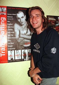 a man standing in front of a wall with a poster on it's side