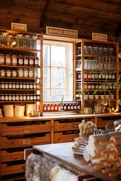 an old fashioned kitchen with lots of jars on the counter and shelves full of food