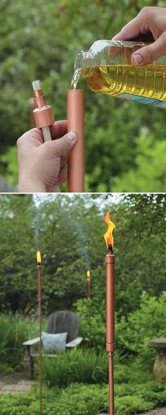 a person is holding a bottle over a fire and some candles in the grass with trees behind them