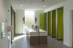 a row of green and white lockers next to each other in a room with windows