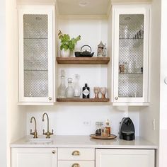 a kitchen with white cabinets and gold handles