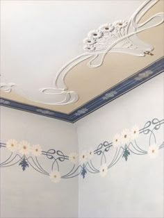 an empty room with white walls and blue trimmings on the ceiling is decorated with flowers