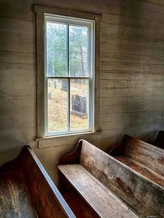 two wooden benches sitting next to a window in a room filled with wood planks