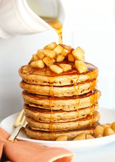 a stack of pancakes with syrup being poured on top