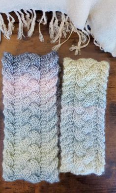 two knitted scarves sitting on top of a wooden floor