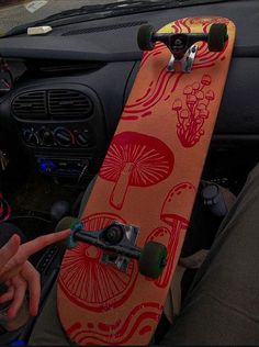 a person holding a skateboard in their lap next to a car steering wheel and dashboard